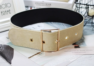 Close-up of beige velvet waist belt with golden square buckle and metal eyelets detail