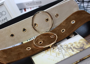 Detail view of velvet wide belts in beige and brown with round golden buckles