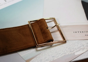 Close-up of brown velvet waist belt featuring a polished golden square metal buckle
