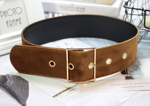 Close-up of wide brown velvet belt with gold rectangular buckle on decorative lifestyle setup