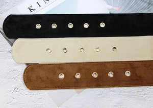 Close-up of velvet waist belts in black, beige, and brown with metallic eyelets