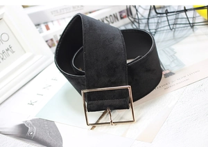 Close-up of a wide black velvet belt featuring a square gold buckle on a stylish background