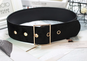 Detailed view of black velvet wide belt with gold square buckle on books background