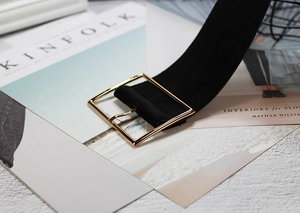 Detail of a black velvet wide waist belt with a golden square metal buckle on magazines