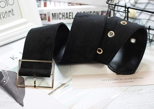 Detail of a black velvet corset belt featuring a gold square buckle and metal eyelets