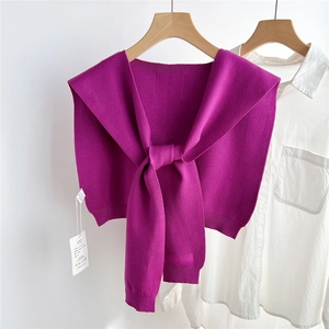 Détail d'un châle tricoté violet foncé avec nœud frontal sur une chemise blanche