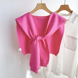 Détail d'un châle tricoté rouge rose avec nœud, bords côtelés et étiquette de marque sur chemise