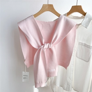 Détail du châle en tricot rose clair avec texture fine et broderie de marque sur l'ourlet