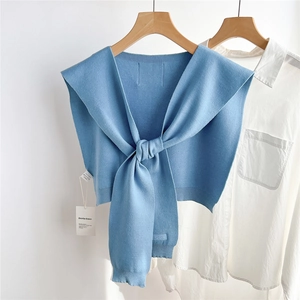 Détail d'un châle en tricot bleu clair avec texture douce sur chemise blanche et cintre