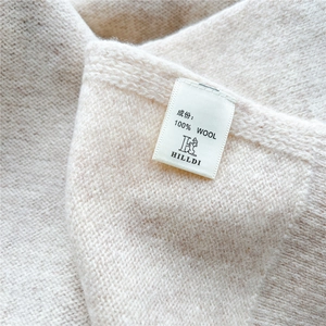 Detail shot of the 100% wool wash label showing premium knit texture on the shawl