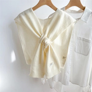 Detail of soft cream 100% wool knitted shawl with fine texture draped on white shirt
