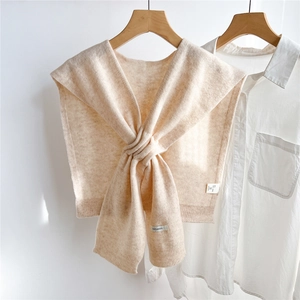 Detail of beige wool knitted shawl showing 100% wool label and ribbed edge texture