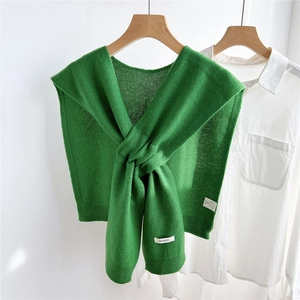 Detail of green knitted wool shawl showing cross-knot style on a white shirt