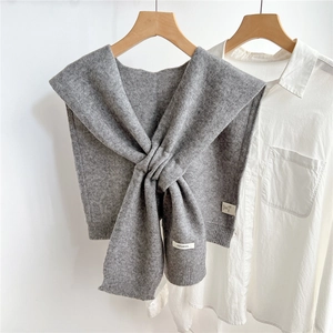 Detail shot of grey knitted wool shawl with 100% wool label on white shirt