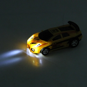Yellow mini RC racing car with functional LED headlights in high contrast dark background