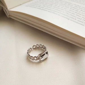 Close-up of S925 sterling silver chain ring with square zircon on an open book