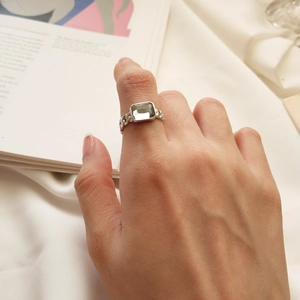 Detailed view of S925 silver ring with rectangle zircon and chain texture on a hand