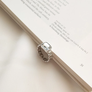 Artistic detail of S925 silver chain ring with rectangular zircon on an open book