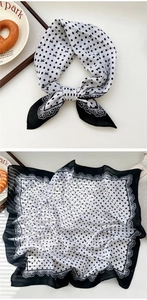 Detail of a vintage black and white polka dot silk scarf with lace edges and bow patterns