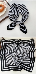 Detail of black and white geometric silk scarf shown tied and laid flat on table