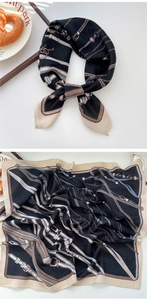 Close-up of silk scarf with vintage chain and belt buckle print on black background