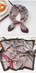Macro detail of satin silk scarf with classic chain and buckle patterns in beige