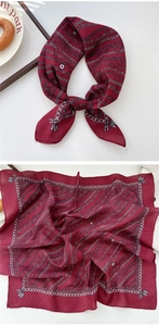 Detail of burgundy silk scarf with vintage silver chain pattern tied in a bow