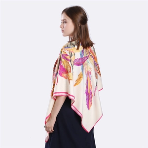Détail d'un grand foulard en soie avec motifs de plumes colorés et bordure rose fine