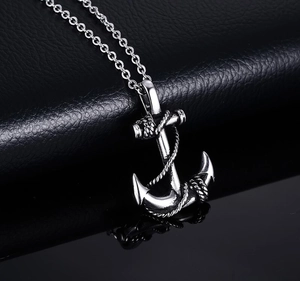 Detailed view of silver anchor pendant with rope texture on a black leather background
