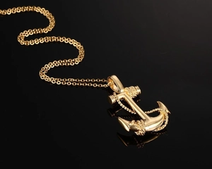 Macro view of a gold anchor pendant with rope details on a classic O-shaped chain