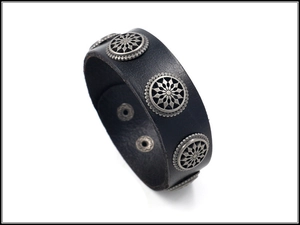 Detail of wide black leather bracelet featuring silver metal floral rivets and snap closure