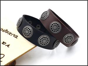 Detail of black and brown leather rivet bracelets with vintage metal floral studs