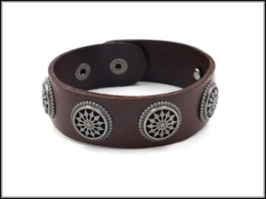 Detail of brown leather cuff bracelet featuring silver star studs and snap closure