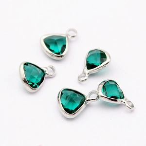 Macro shot of green crystal faceted triangle pendants with silver metal bezel setting