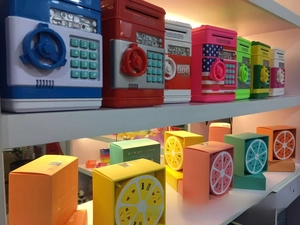 Mini ATM piggy banks and safes with digital keypads displayed in various bright colors
