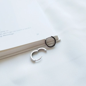 Orecchini a cerchio minimalisti in argento S925 su panno bianco e libro aperto