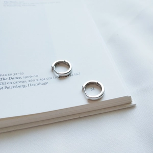 Orecchini a cerchio minimalisti in argento 925 su un libro d'arte aperto