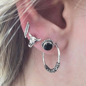 Gros plan détaillé d'un ensemble de boucles d'oreilles plume et crâne de taureau