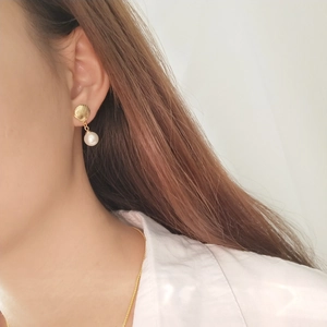 Detailed view of 925 silver shell stud earring with pearl drop on a female model
