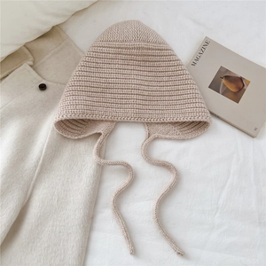Détail d'un bonnet en laine tricoté beige avec cache-oreilles et texture côtelée