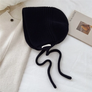Détail du bonnet en laine noire montrant l'étiquette 100 % laine et le tissage épais