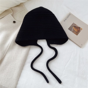 Détail du bonnet en tricot noir épais avec de longs liens et une texture côtelée en relief