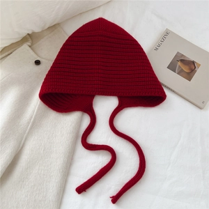Détails de texture du bonnet en laine bordeaux tricoté avec nœud et protection d'oreilles