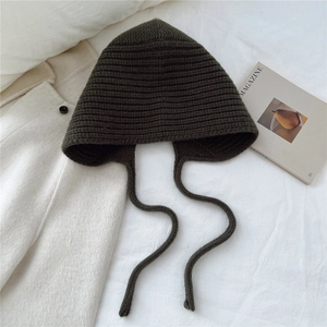 Gros plan du bonnet en laine tricotée vert olive avec texture épaisse et longs liens
