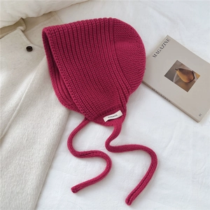 Détail de l'étiquette 100 % laine sur un bonnet en tricot fuchsia avec cache-oreilles