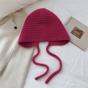 Détails de la texture du bonnet en laine rose avec cache-oreilles et larges lanières