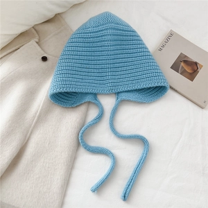 Texture de tricot détaillée du bonnet en laine bleu clair avec cache-oreilles et liens