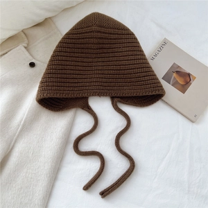 Détail du bonnet en laine tricoté café noir avec texture rayée et longues lanières à nouer