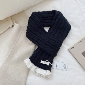 Close-up of black cable knit scarf with white lace trim and minimalist brand tag