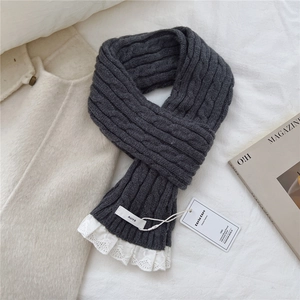 Detail of dark grey knit scarf featuring thick cable stitch and white lace trim detail